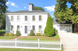 White two story colonial house with white picket fence