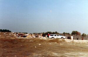 Dump with white Chevy wagon and person in red shirt