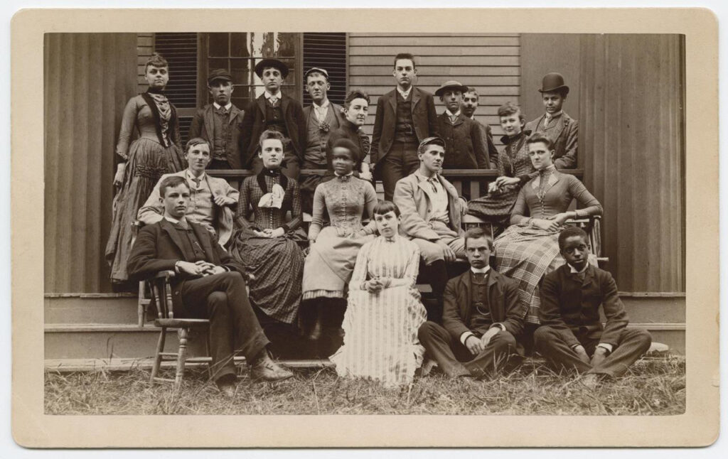 Group of men and women of different races sitting outside building