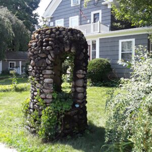 Stone well casing in front of blue house