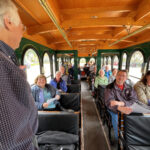 People on old time trolley looking at narrator