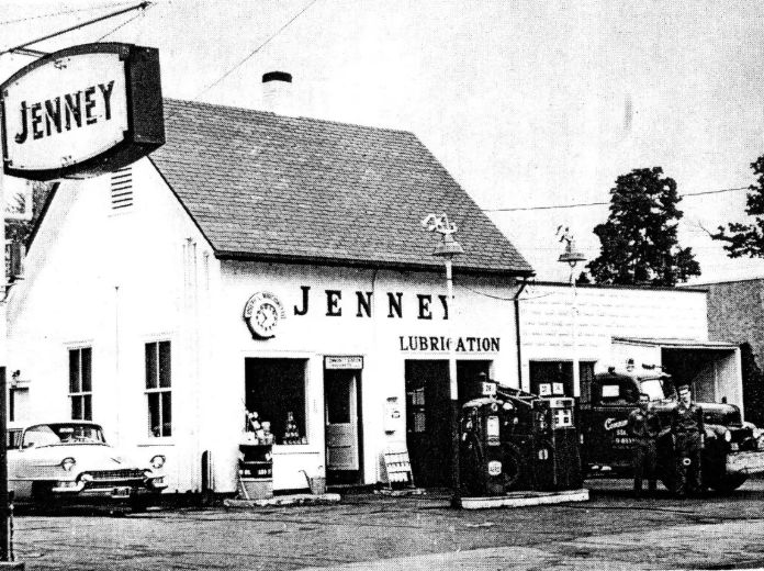 Black and white photo of gas station with men standing in front