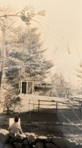Artist Byron Reed seated in front of easel painting picture of a windmill