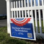 Red white and blue sign in front of picket fence