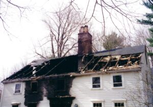 House with burnt out roof and black smoke on siding