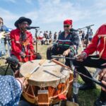 Native americans seated in a circle around a large drum.